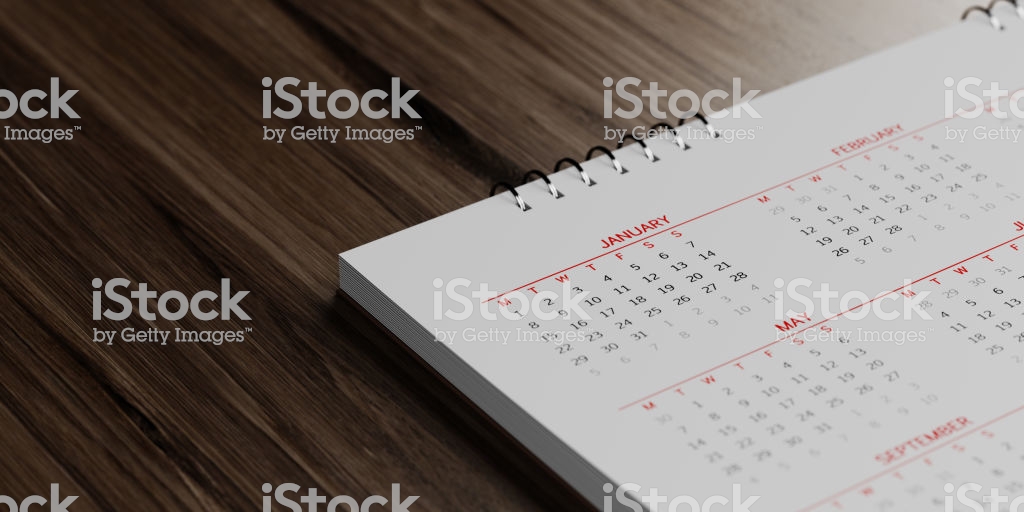 White calendar on brown reflective wood surface. January, May and February months are visible. Panoramic composition with copy space. Calendar and reminder concept with selective focus.